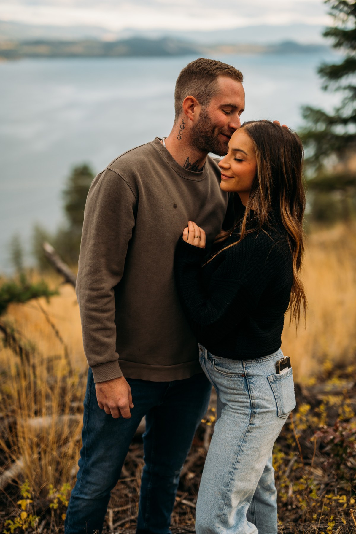 Rachel and Ryan portraits story frame 3: Okanagan couples portraits with dirt bikes, lake and mountain views, autumn sun, standing portraits and champagne celebration.