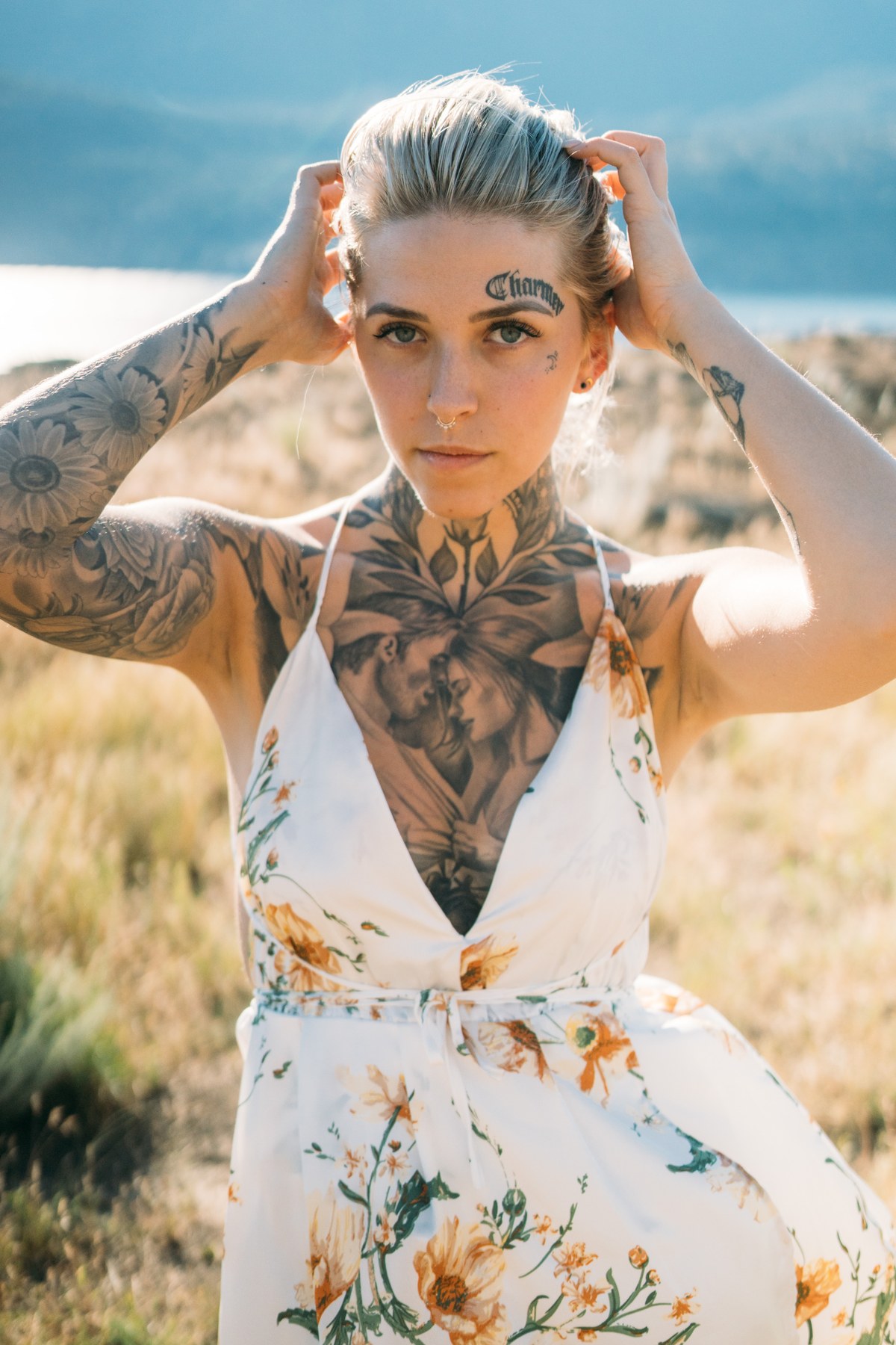 Rayleigh by Knox portraits story frame 1: Knox Mountain portraits in Kelowna with white floral dress, tattoo detail, reeds, water, sunlight and a stronger summer edge.