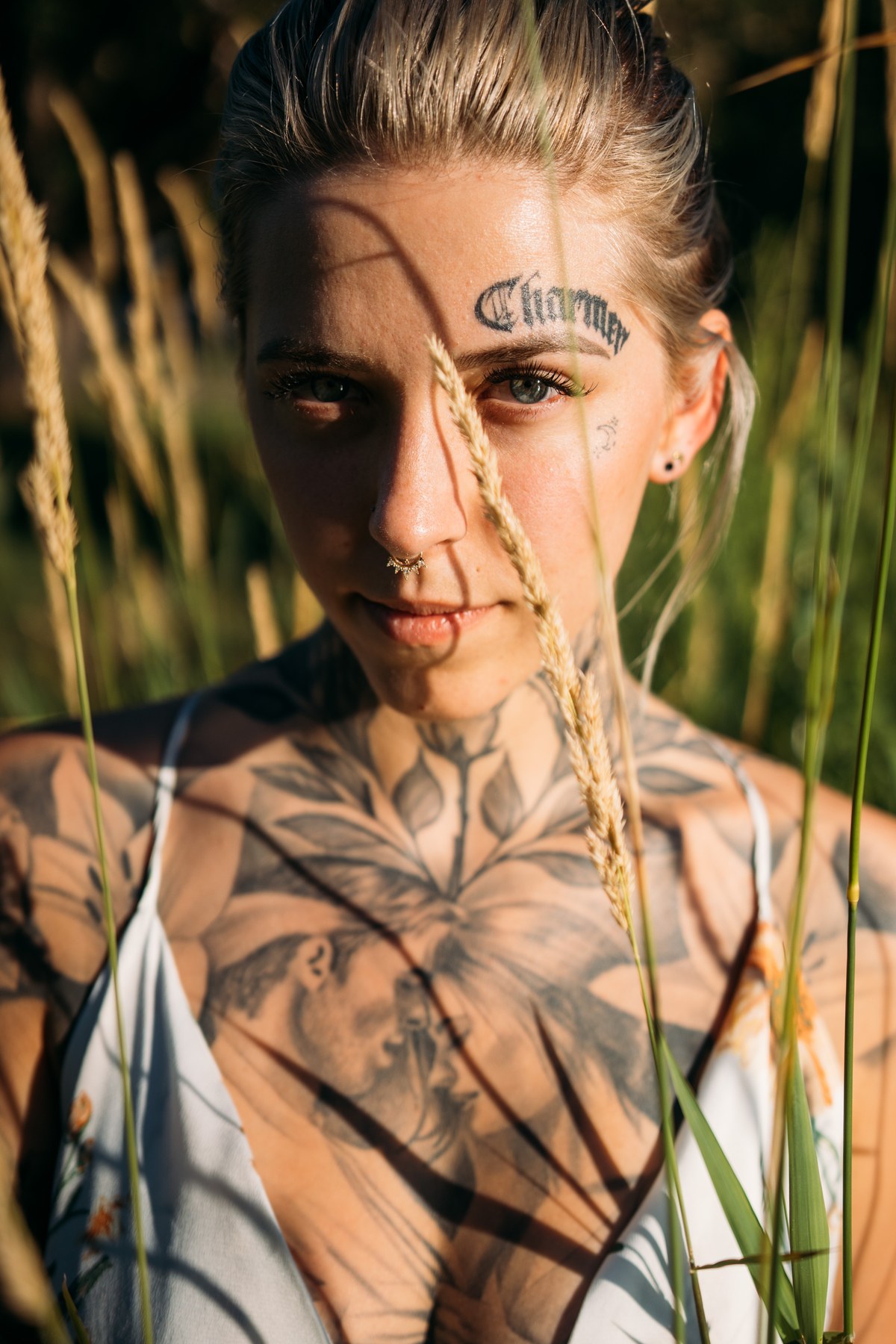 Rayleigh by Knox portraits story frame 5: Knox Mountain portraits in Kelowna with white floral dress, tattoo detail, reeds, water, sunlight and a stronger summer edge.