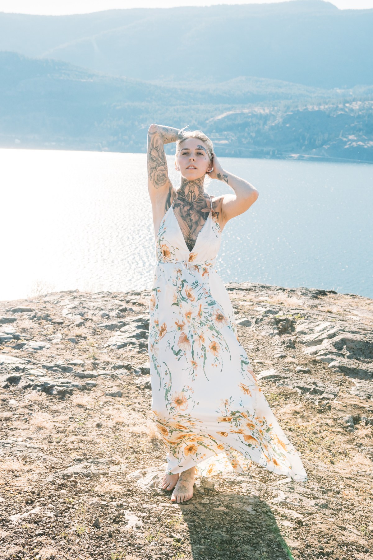Rayleigh by Knox portraits story frame 6: Knox Mountain portraits in Kelowna with white floral dress, tattoo detail, reeds, water, sunlight and a stronger summer edge.