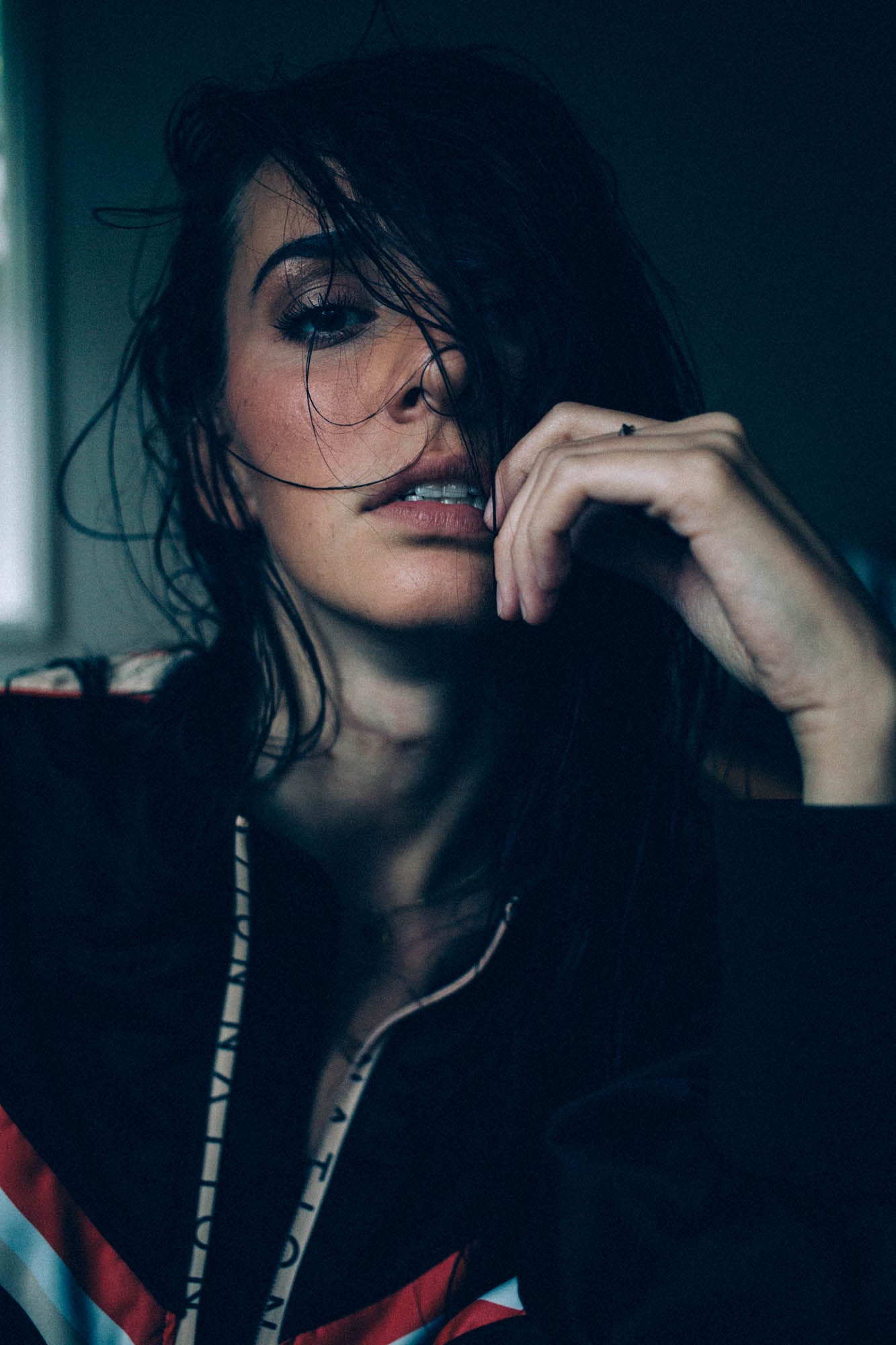 Rebecca in Smoke portraits story frame 1: A dark Kelowna portrait story for Rebecca with window light, smoke, denim, close expression and a low-key editorial mood.