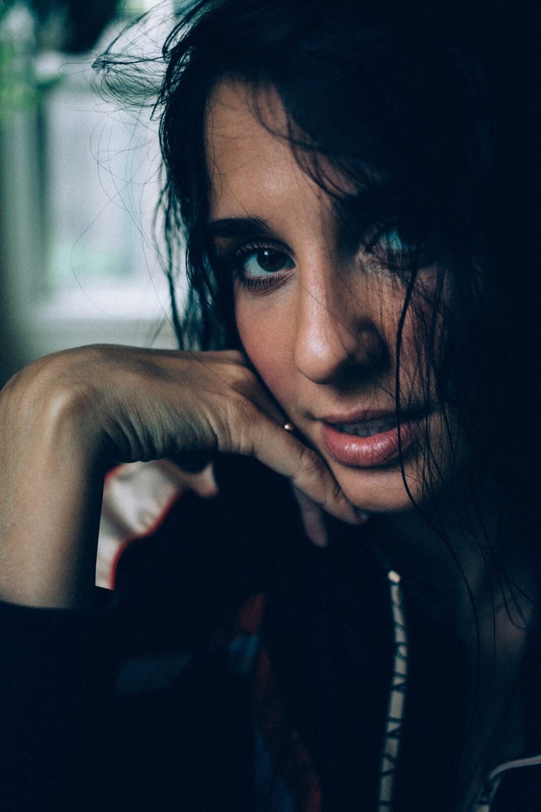 Rebecca in Smoke portraits story frame 6: A dark Kelowna portrait story for Rebecca with window light, smoke, denim, close expression and a low-key editorial mood.