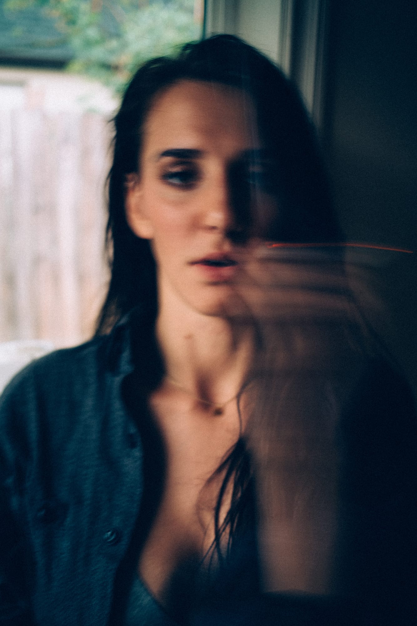 Rebecca in Smoke portraits story frame 19: A dark Kelowna portrait story for Rebecca with window light, smoke, denim, close expression and a low-key editorial mood.