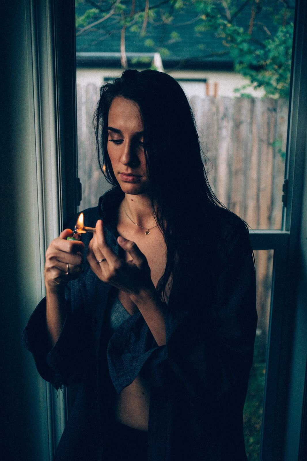 Rebecca in Smoke portraits story frame 16: A dark Kelowna portrait story for Rebecca with window light, smoke, denim, close expression and a low-key editorial mood.