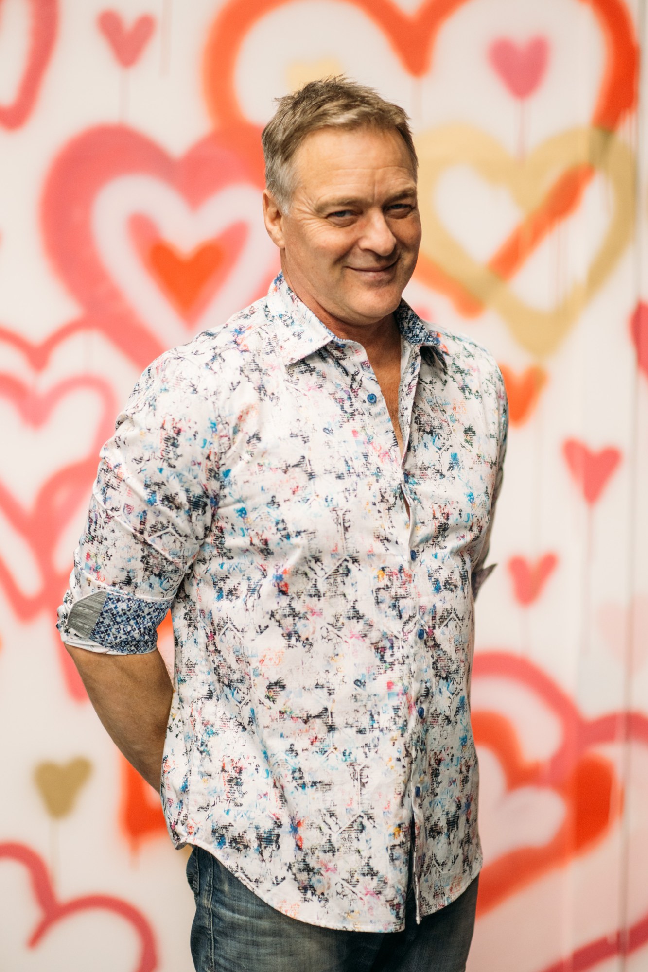 Roark beside a brightly painted wall of hearts