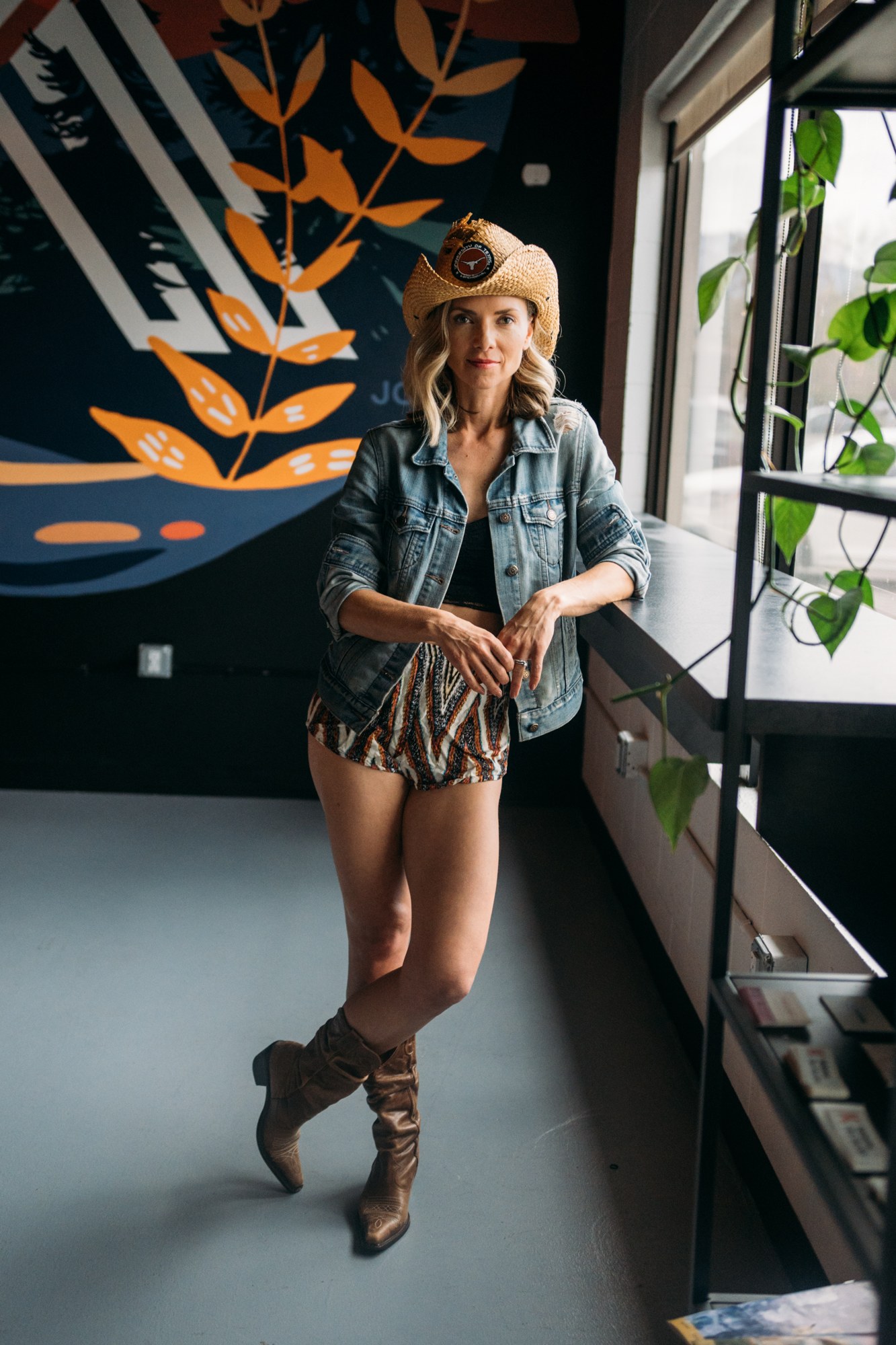 Sarah in a cowboy hat beside the studio windows