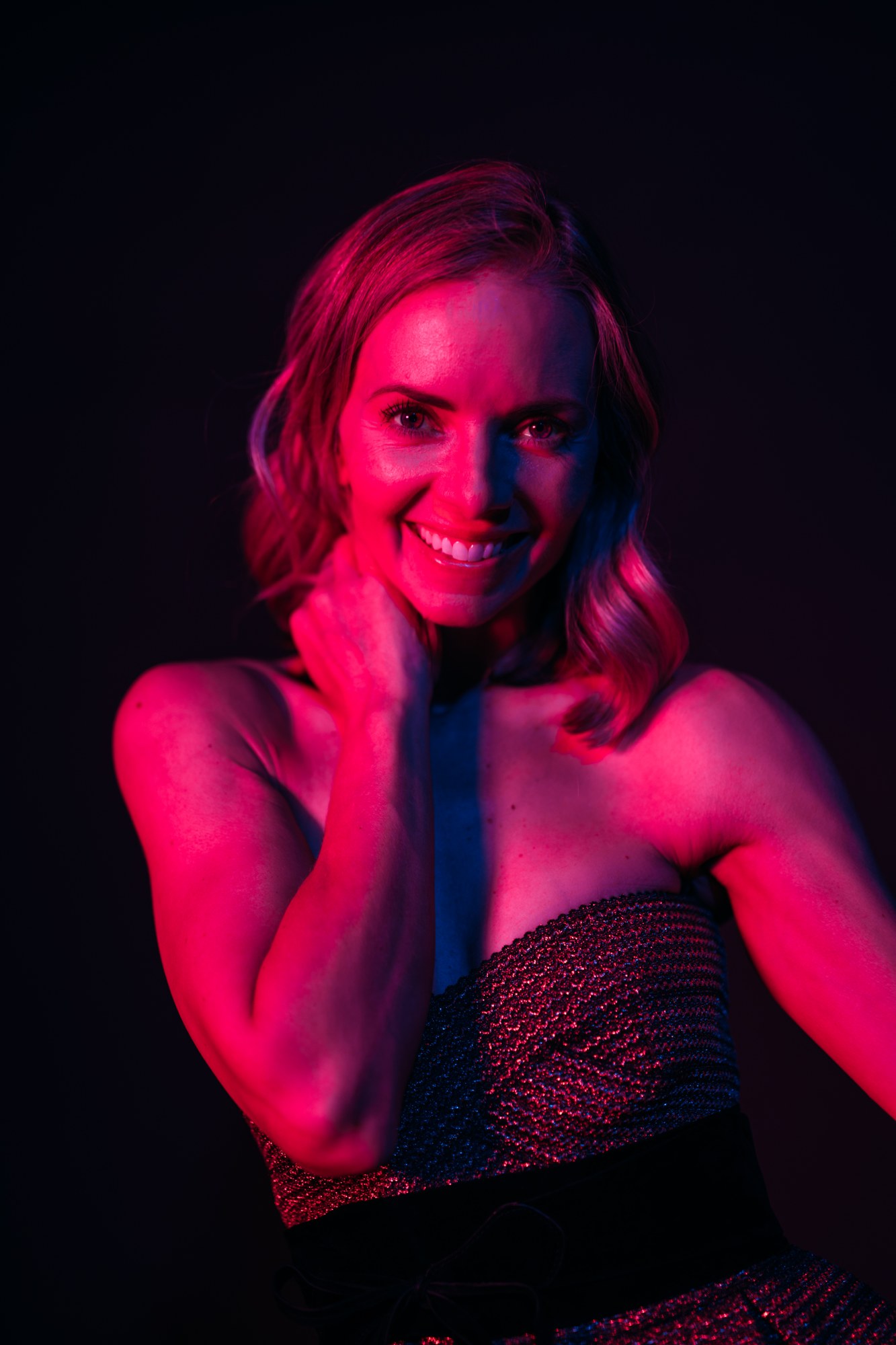 Sarah smiling in magenta studio light