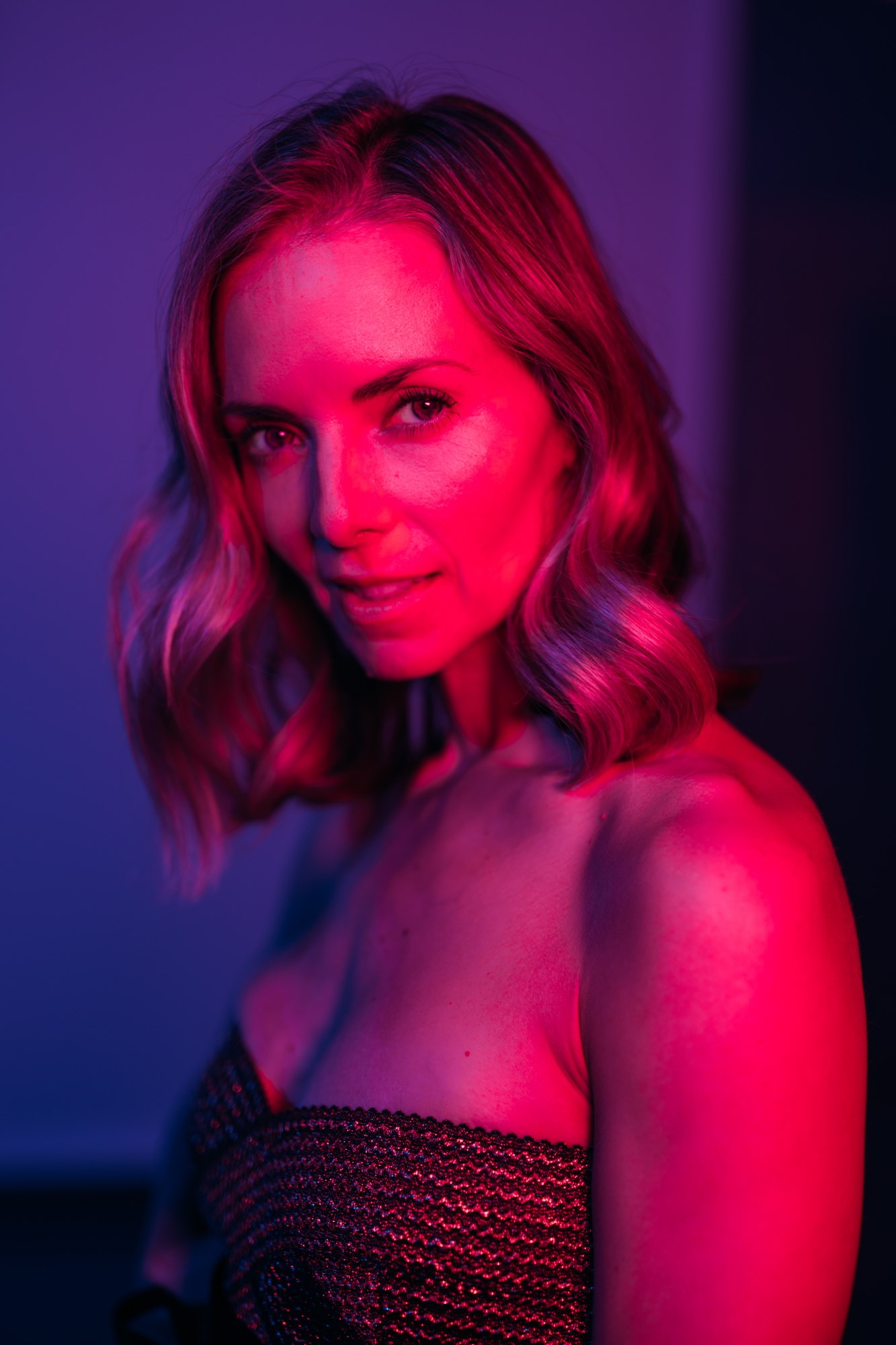 Sarah in a gold dress under blue and pink studio lights