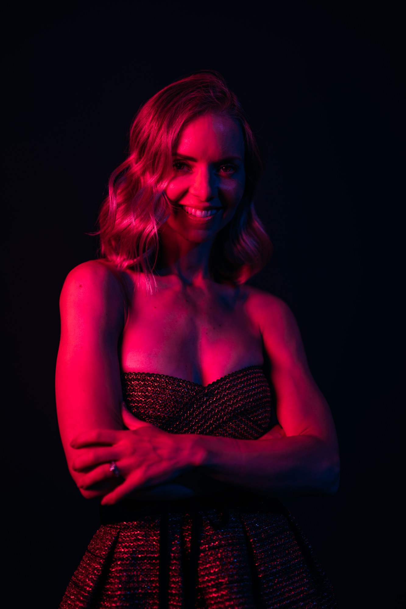 Sarah in red studio light with her arms crossed