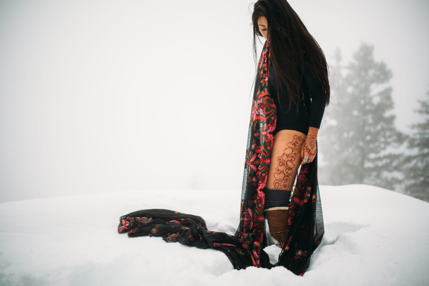 Sarah in the Snow portraits story frame 6: A winter portrait session for Sarah in Kelowna, with snow, black wardrobe, sheer floral fabric, whiteout atmosphere and bold movement in a cold landscape.