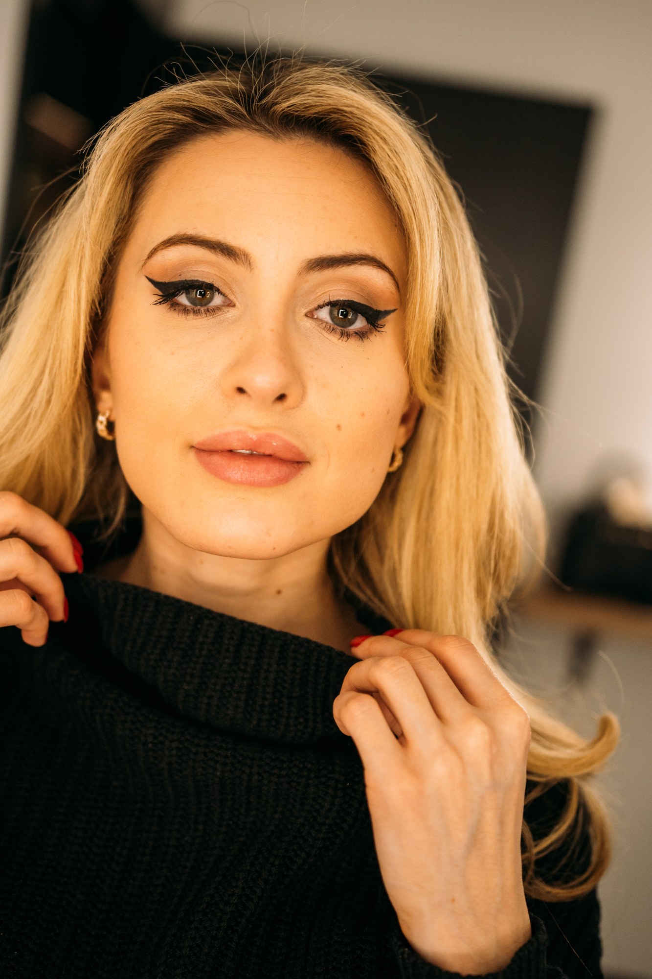 Shanelle in a black sweater with her hands near her collar