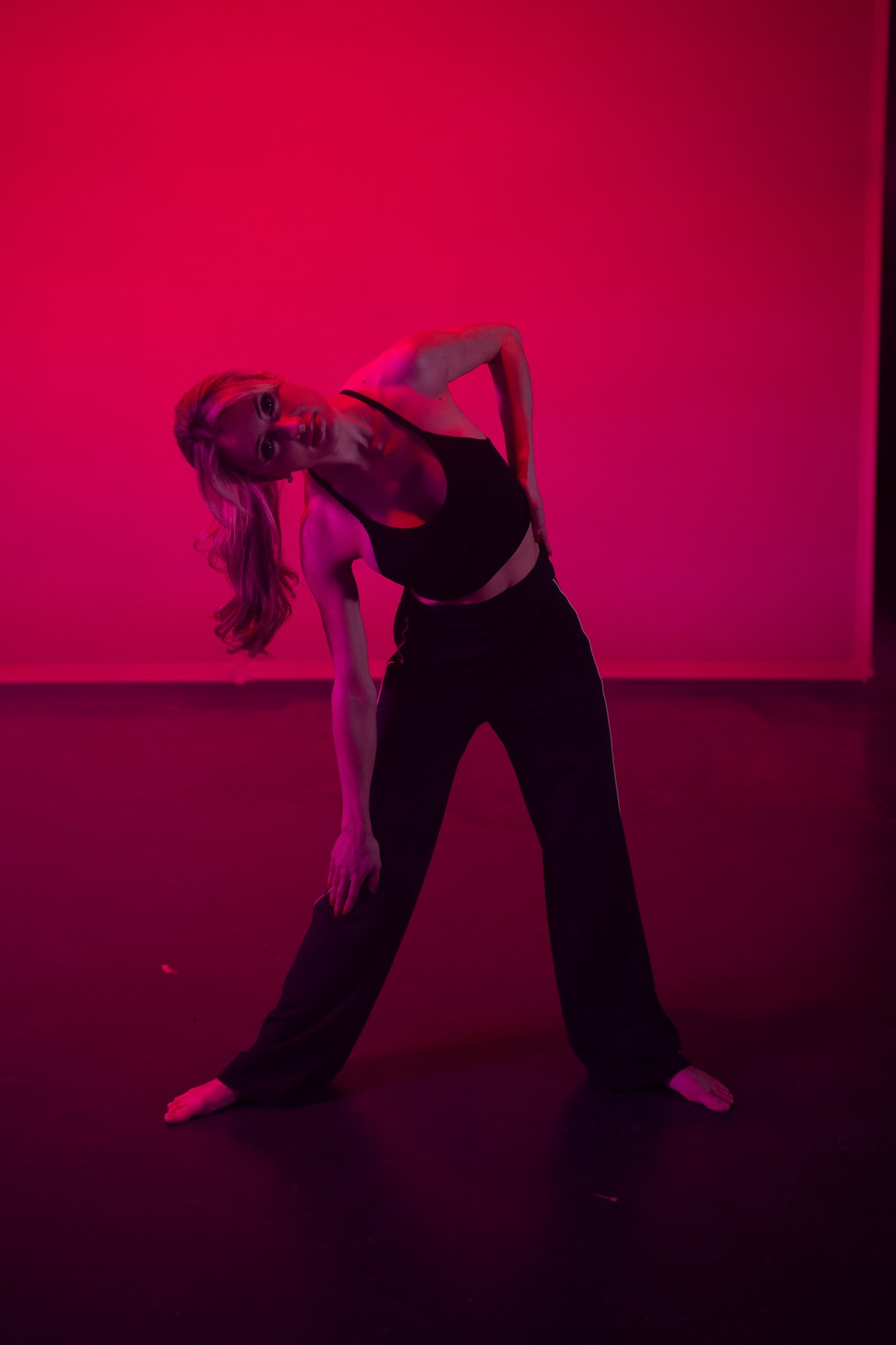 Shanelle reaching sideways under pink studio light