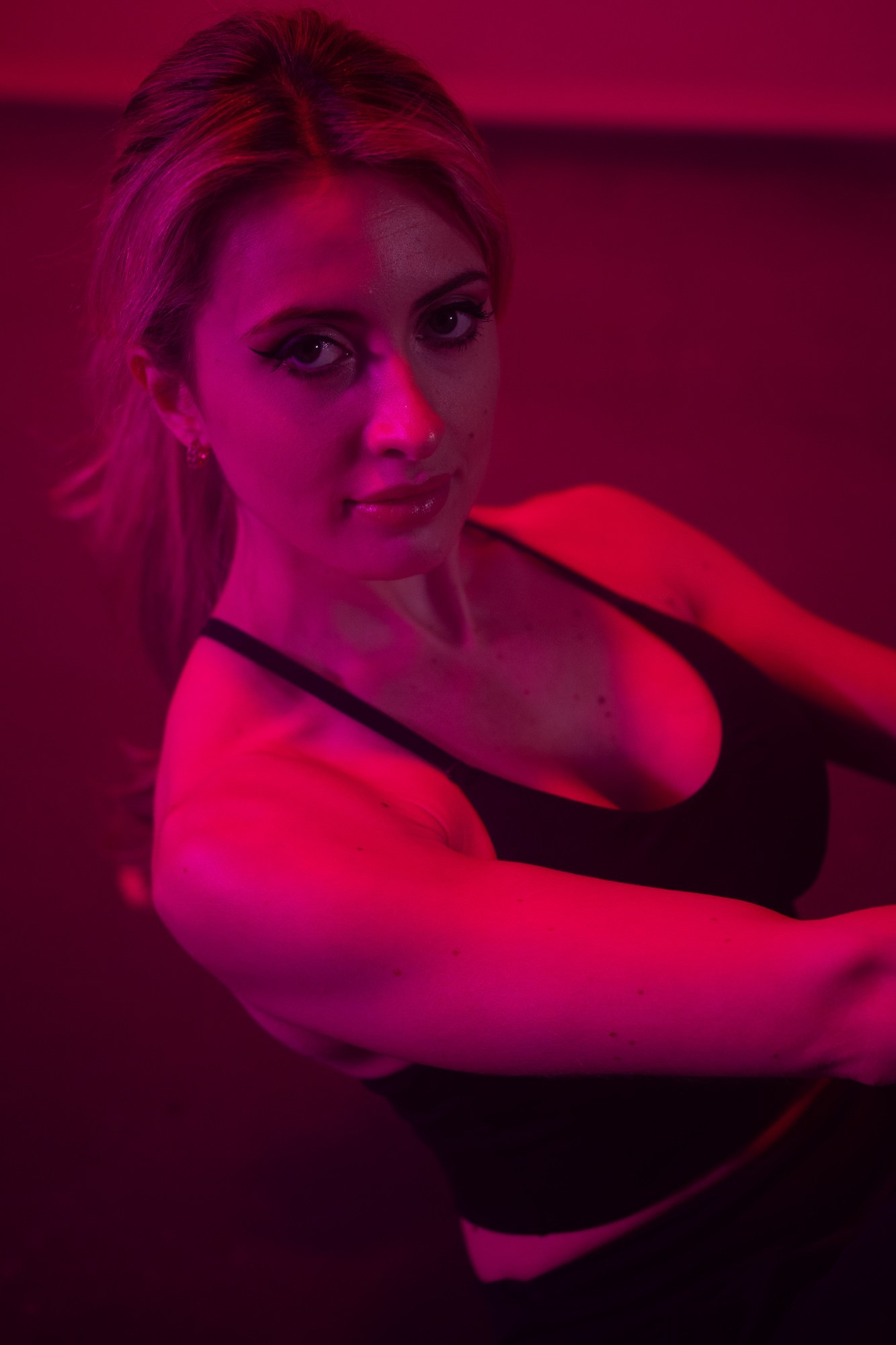 Shanelle seated in magenta light looking toward the camera