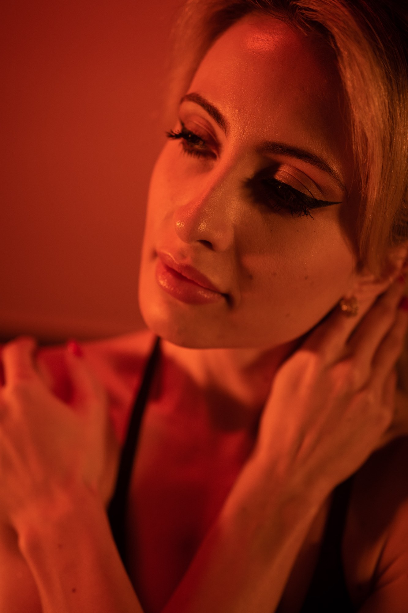 Shanelle with her eyes closed and hands near her shoulder in amber light