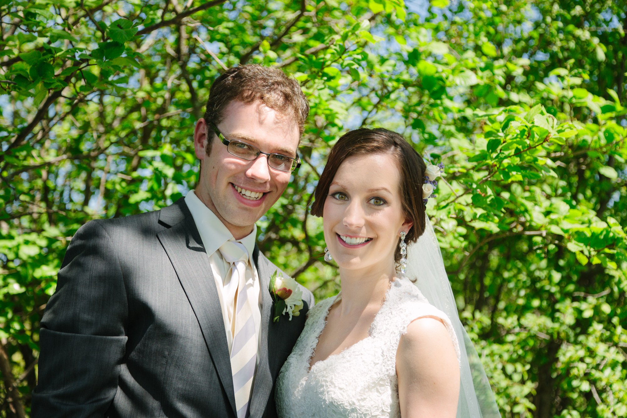 Shannon and Ehren smiling beneath green foliage.