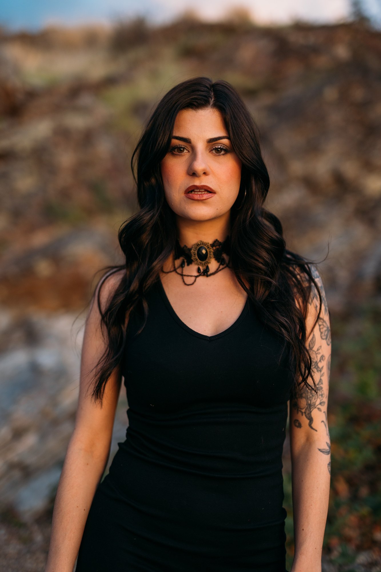 Sophia — direct portrait in a black dress beside the rock face