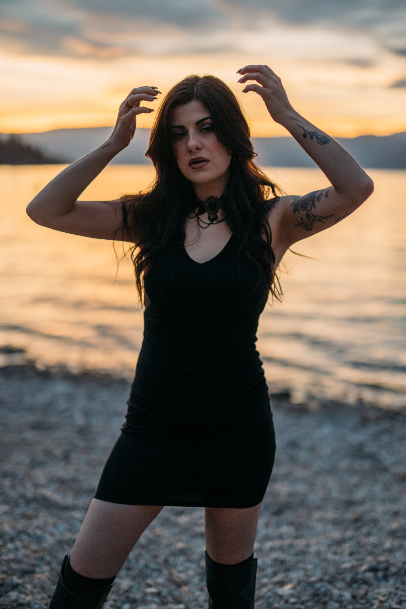 Sophia — both hands in her hair against the evening sky