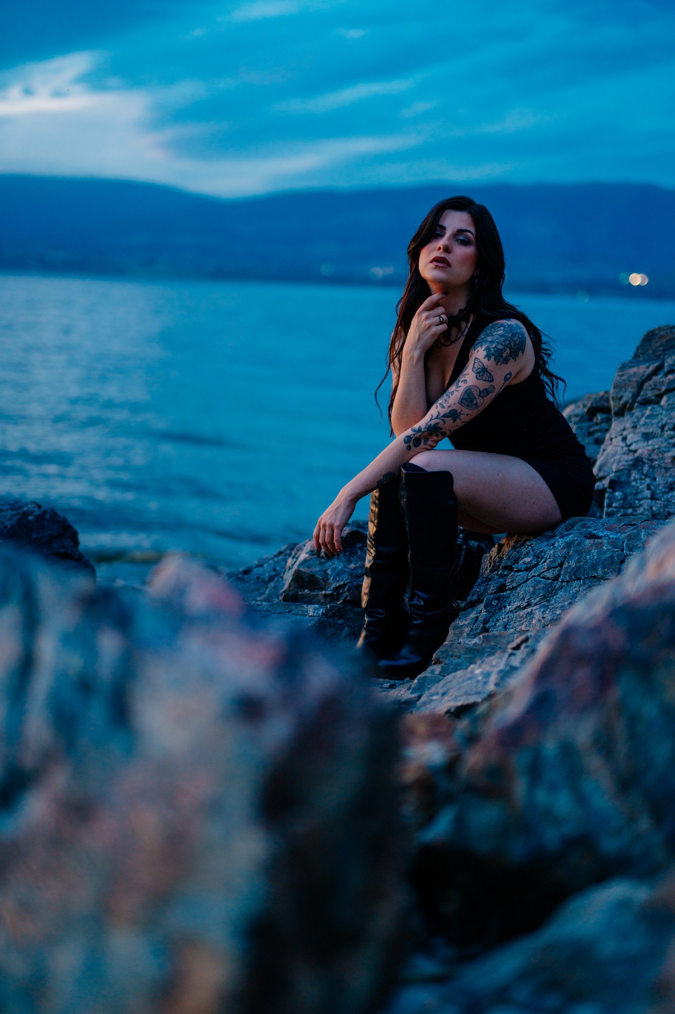 Sophia — crouching on a shoreline rock at blue hour