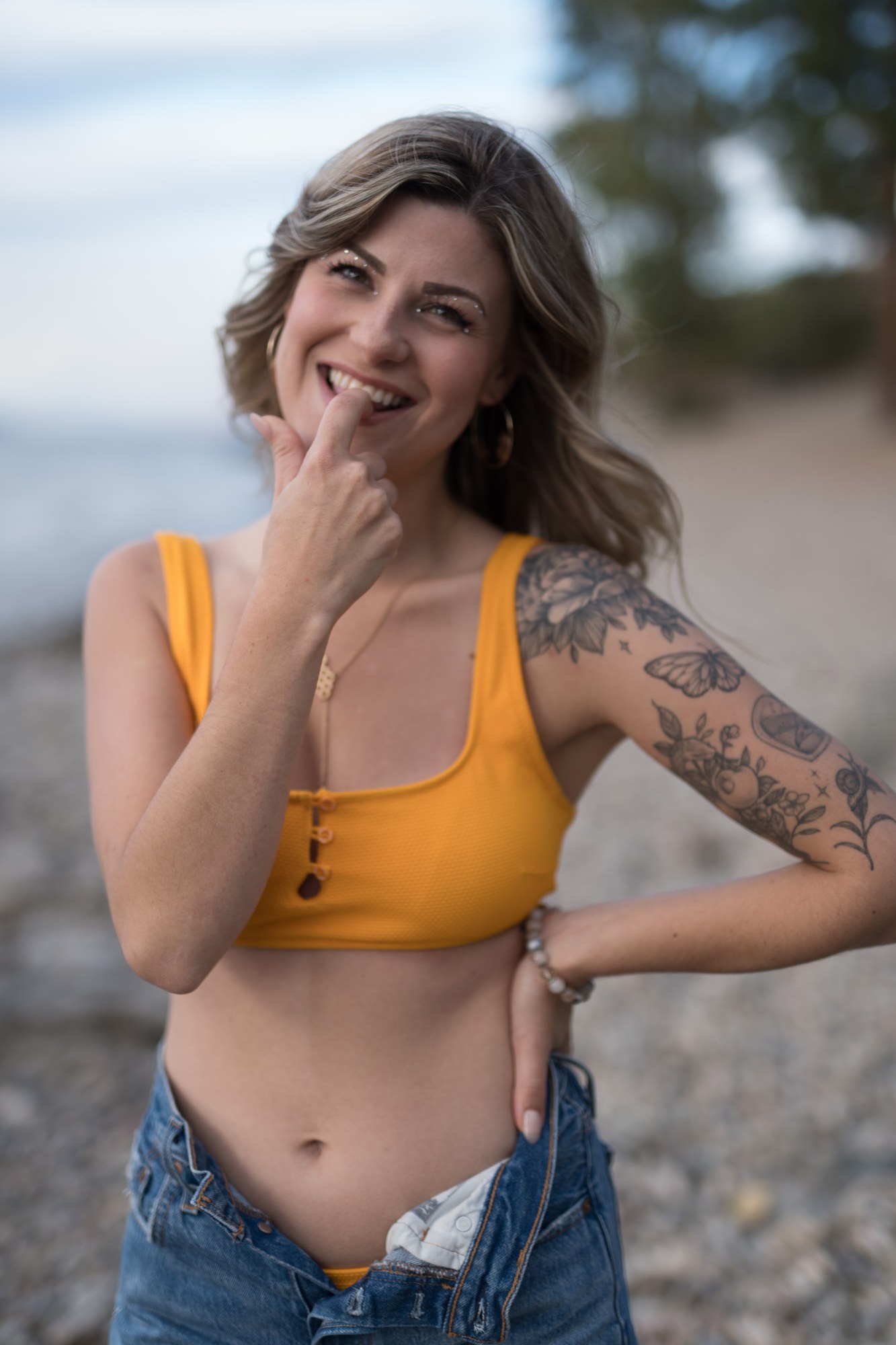 Sophia at Bertram Creek Park: Smiling close portrait with a finger beside the lips.