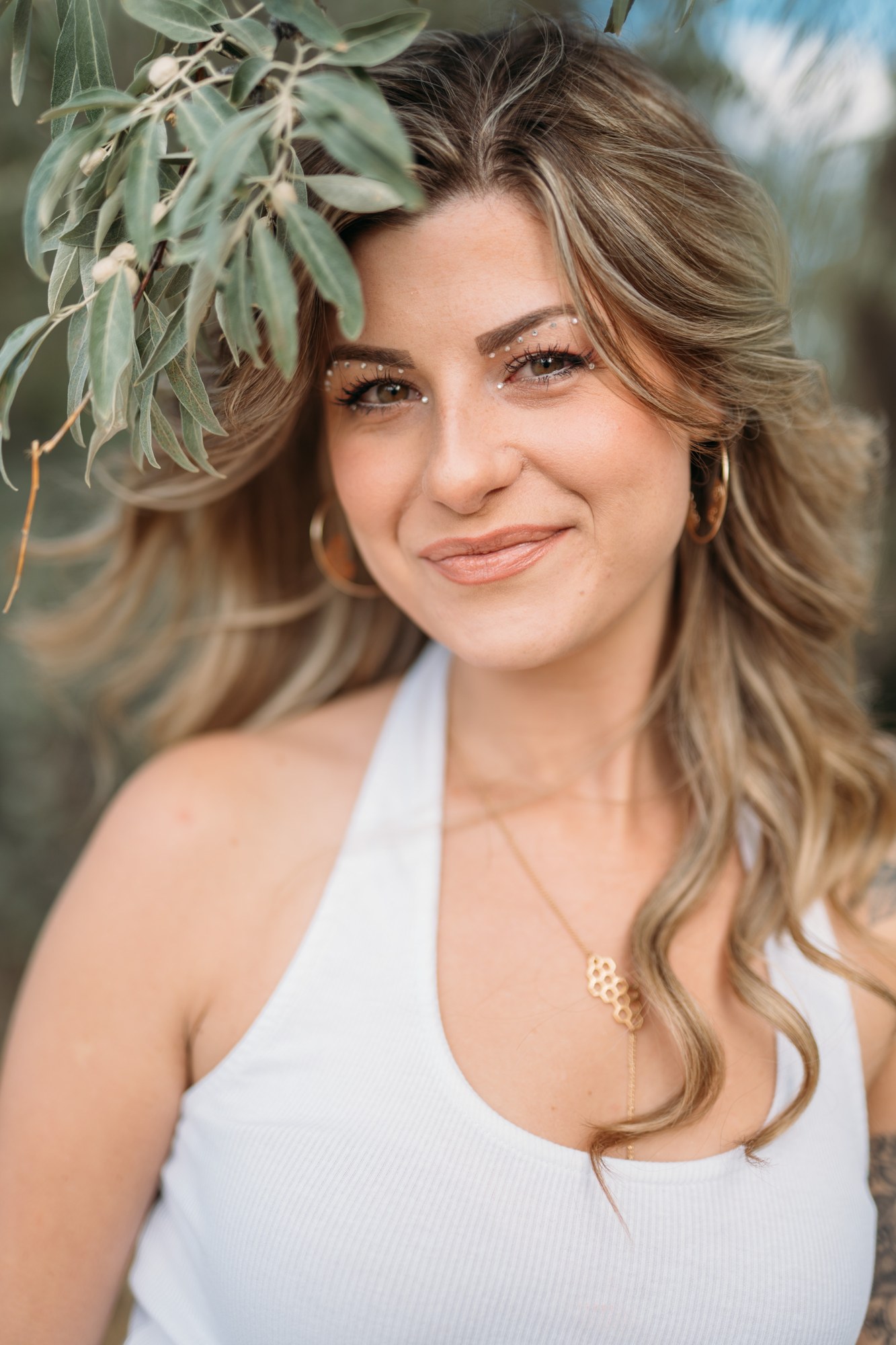 Sophia smiling beneath willow branches, with small gems above her eyes.