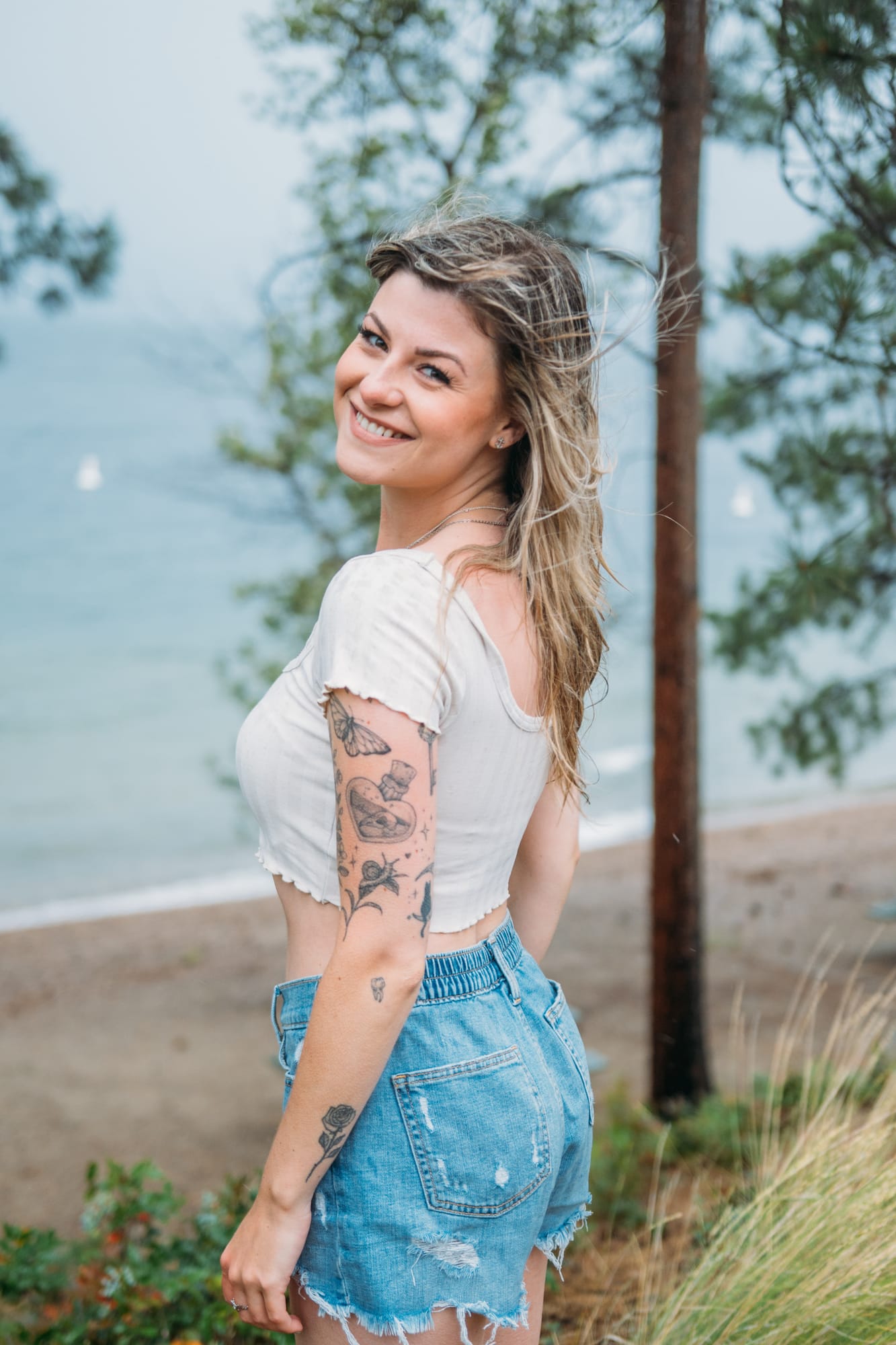 Sophia by the Lake portraits story frame 11: A multi-outfit Okanagan location session with water, trees, shoreline, denim and red swimwear woven into a summer portrait story.