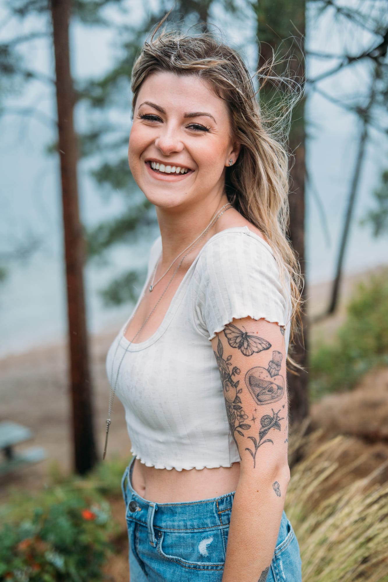 Sophia by the Lake portraits story frame 12: A multi-outfit Okanagan location session with water, trees, shoreline, denim and red swimwear woven into a summer portrait story.