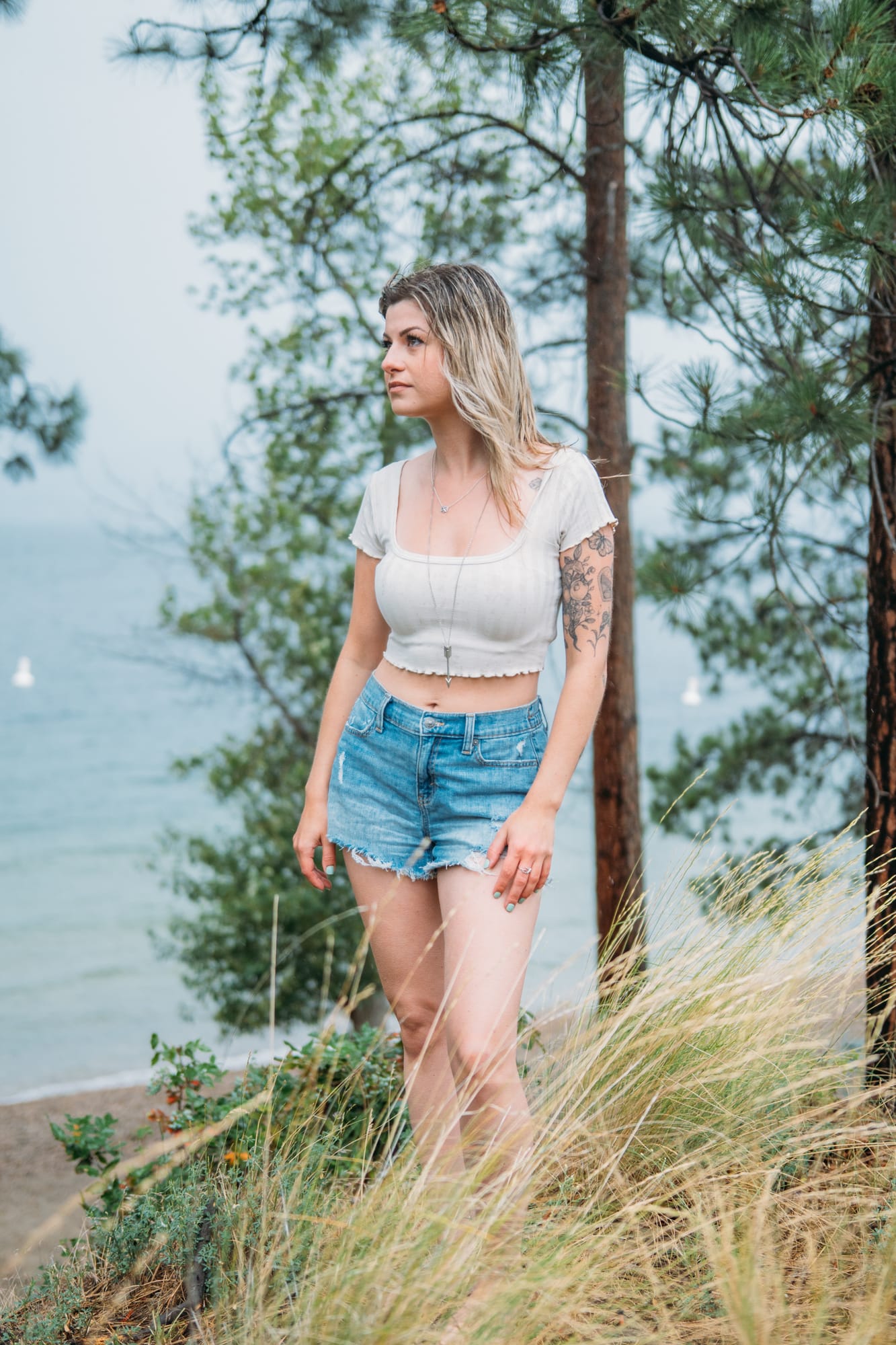 Sophia by the Lake portraits story frame 13: A multi-outfit Okanagan location session with water, trees, shoreline, denim and red swimwear woven into a summer portrait story.