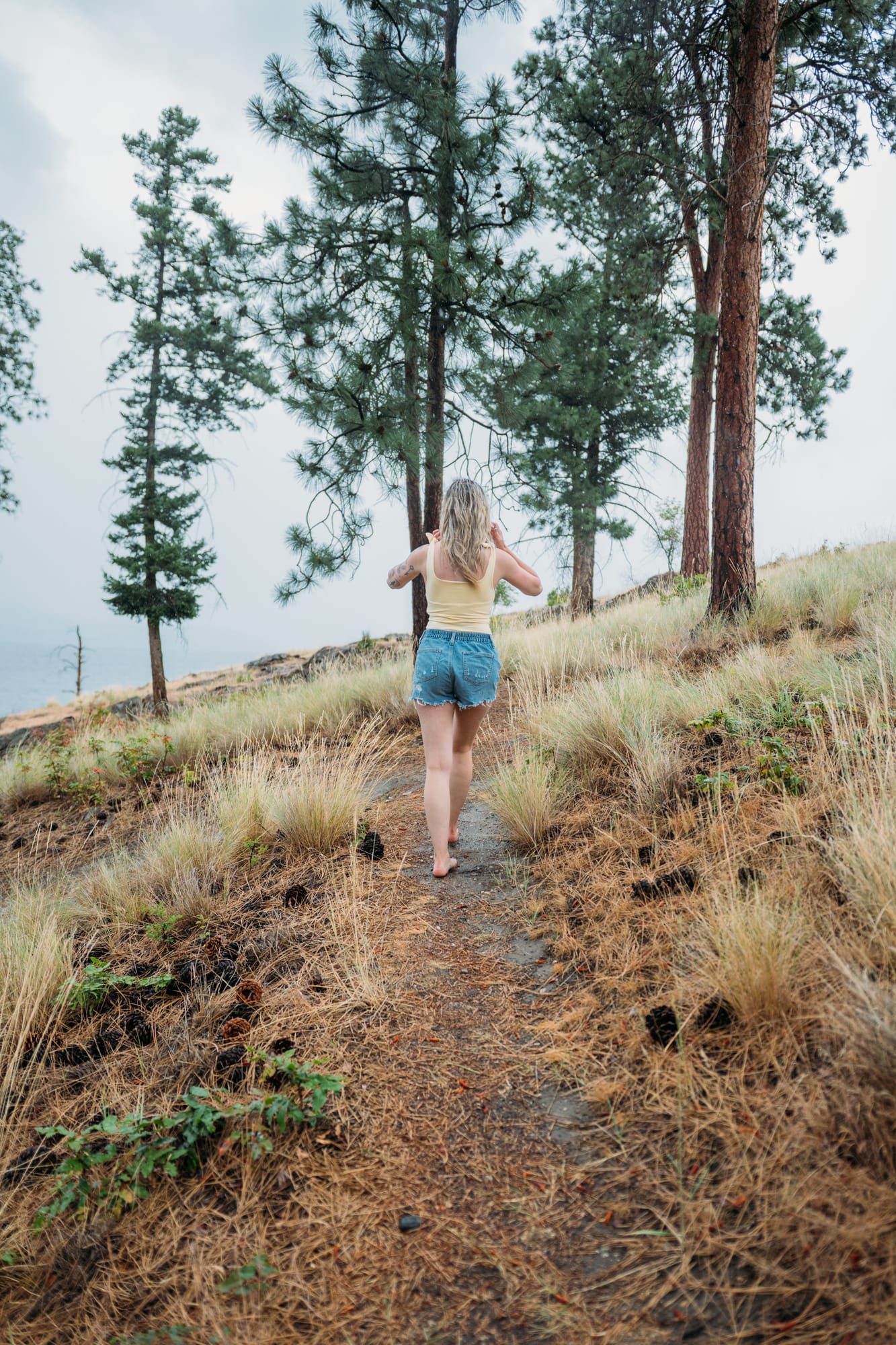 Sophia by the Lake portraits story frame 16: A multi-outfit Okanagan location session with water, trees, shoreline, denim and red swimwear woven into a summer portrait story.