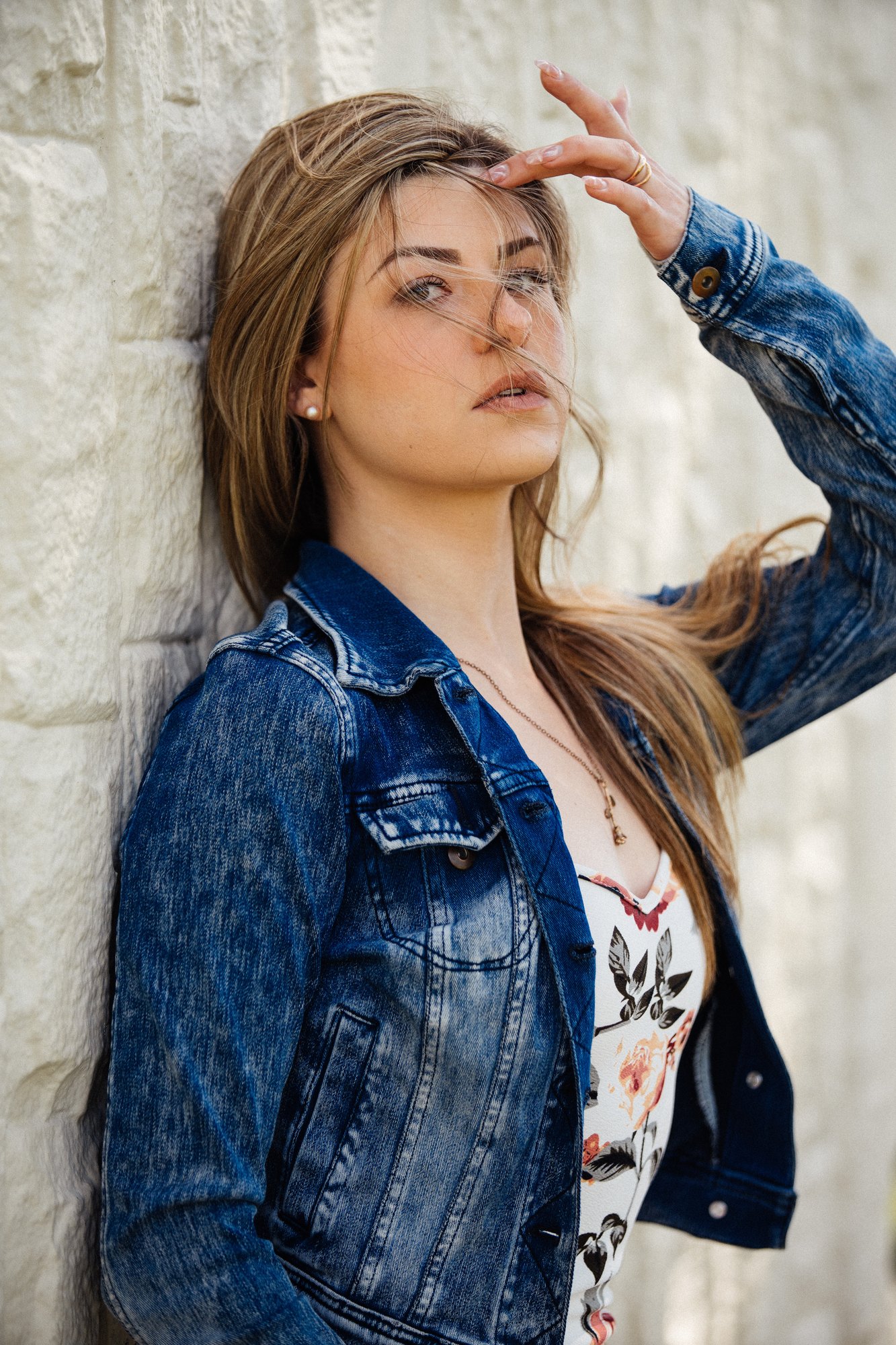 Sophia — close denim-jacket portrait beside the wall