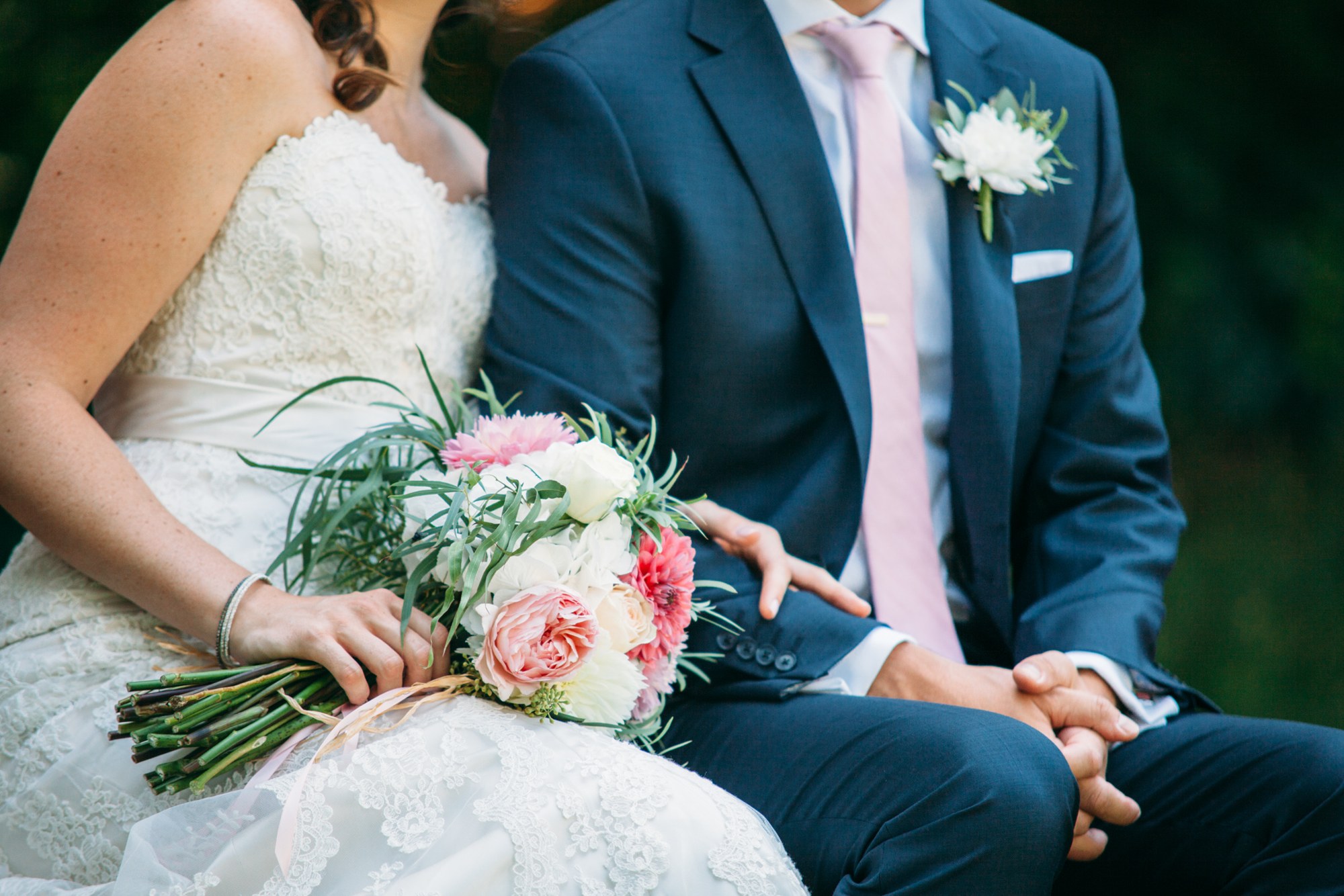 Steph & Taylor: Joined hands and bouquet while seated together.