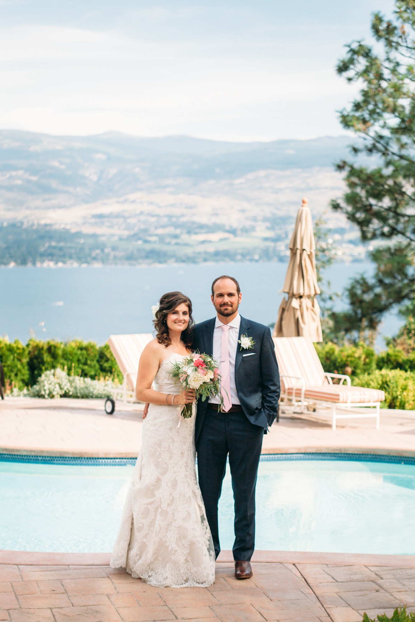 Steph & Taylor: Full couple portrait with the lake beyond the pool.