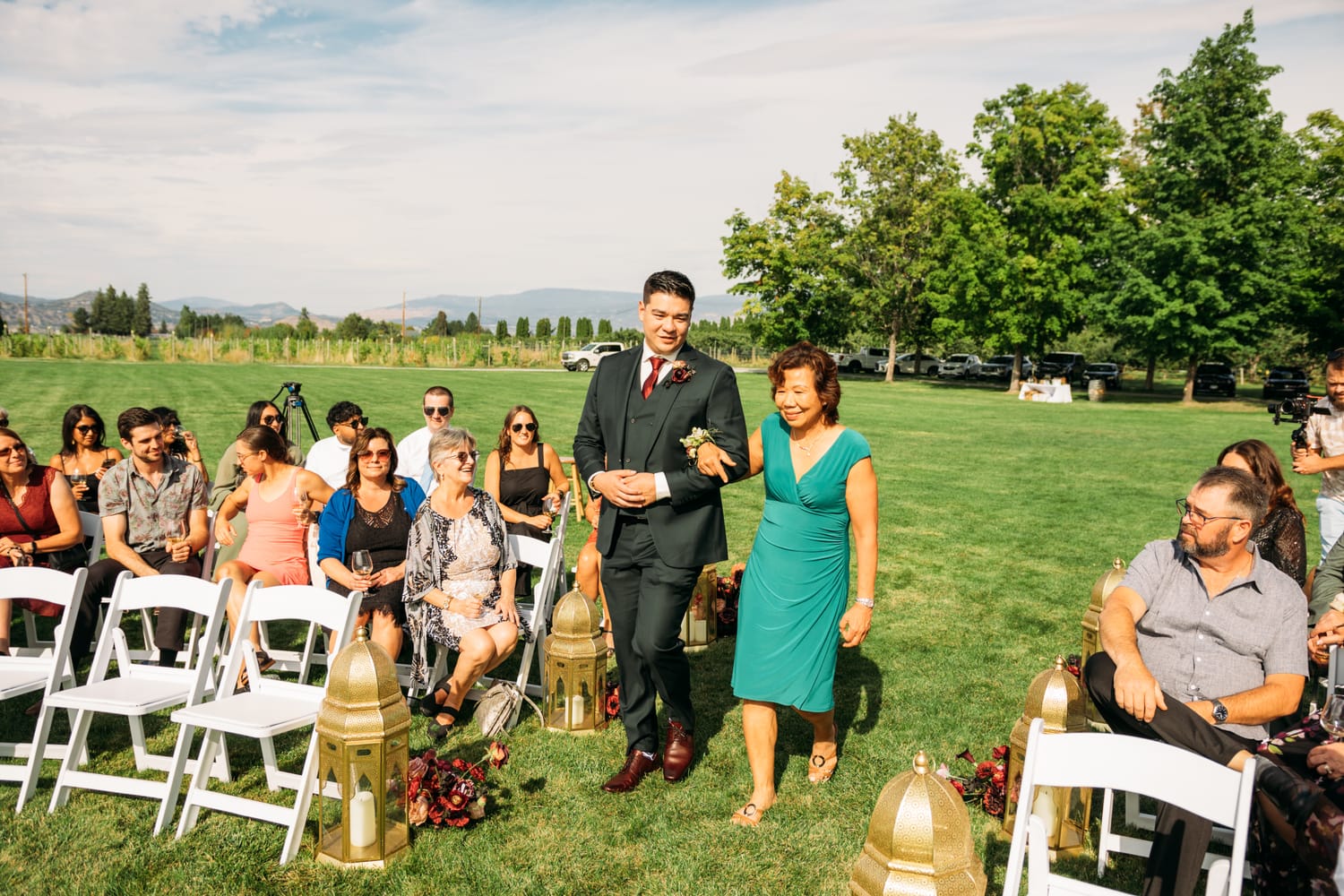 Taryn and Kai weddings story frame 11: An Okanagan vineyard wedding with ceremony, veil, guests, family, makeup by Guisachan Esthetics, and laughter woven through the altar moments..