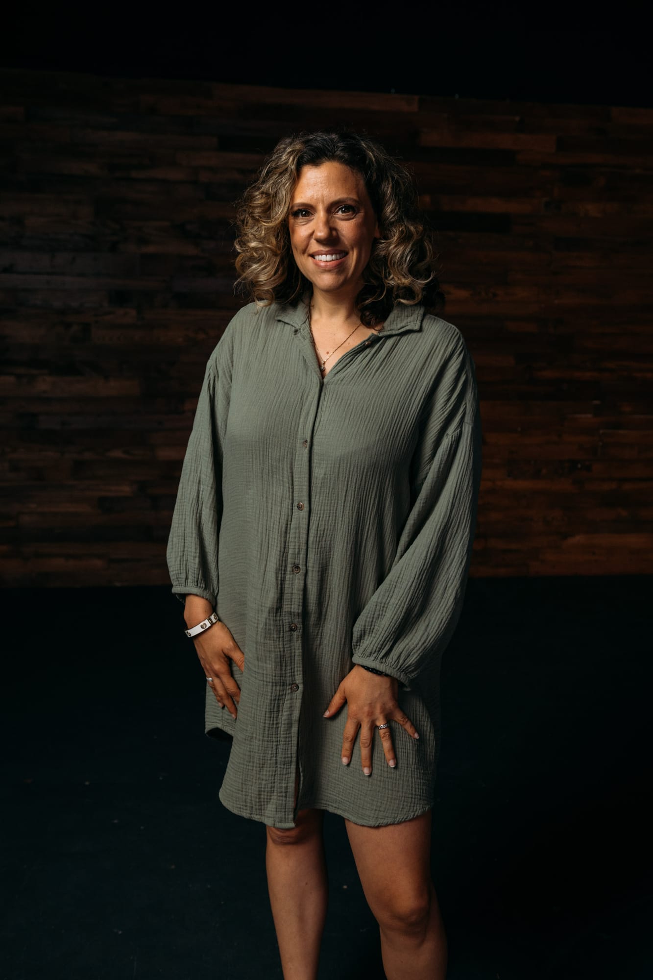 Trisha Miltimore corporate story frame 3: Personal-brand portraits for Trisha Miltimore in Kelowna, moving from clean business profile images into darker wood-wall portraits with black wardrobe and confident brand range..