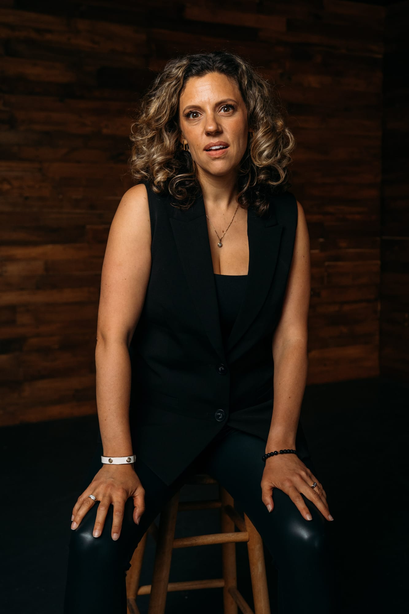 Trisha Miltimore corporate story frame 7: Personal-brand portraits for Trisha Miltimore in Kelowna, moving from clean business profile images into darker wood-wall portraits with black wardrobe and confident brand range..