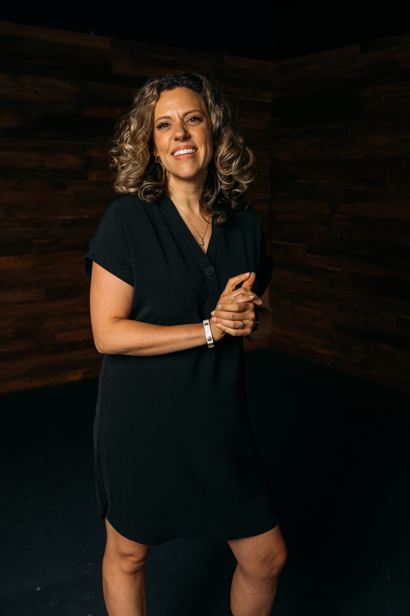 Trisha Miltimore corporate story frame 11: Personal-brand portraits for Trisha Miltimore in Kelowna, moving from clean business profile images into darker wood-wall portraits with black wardrobe and confident brand range..
