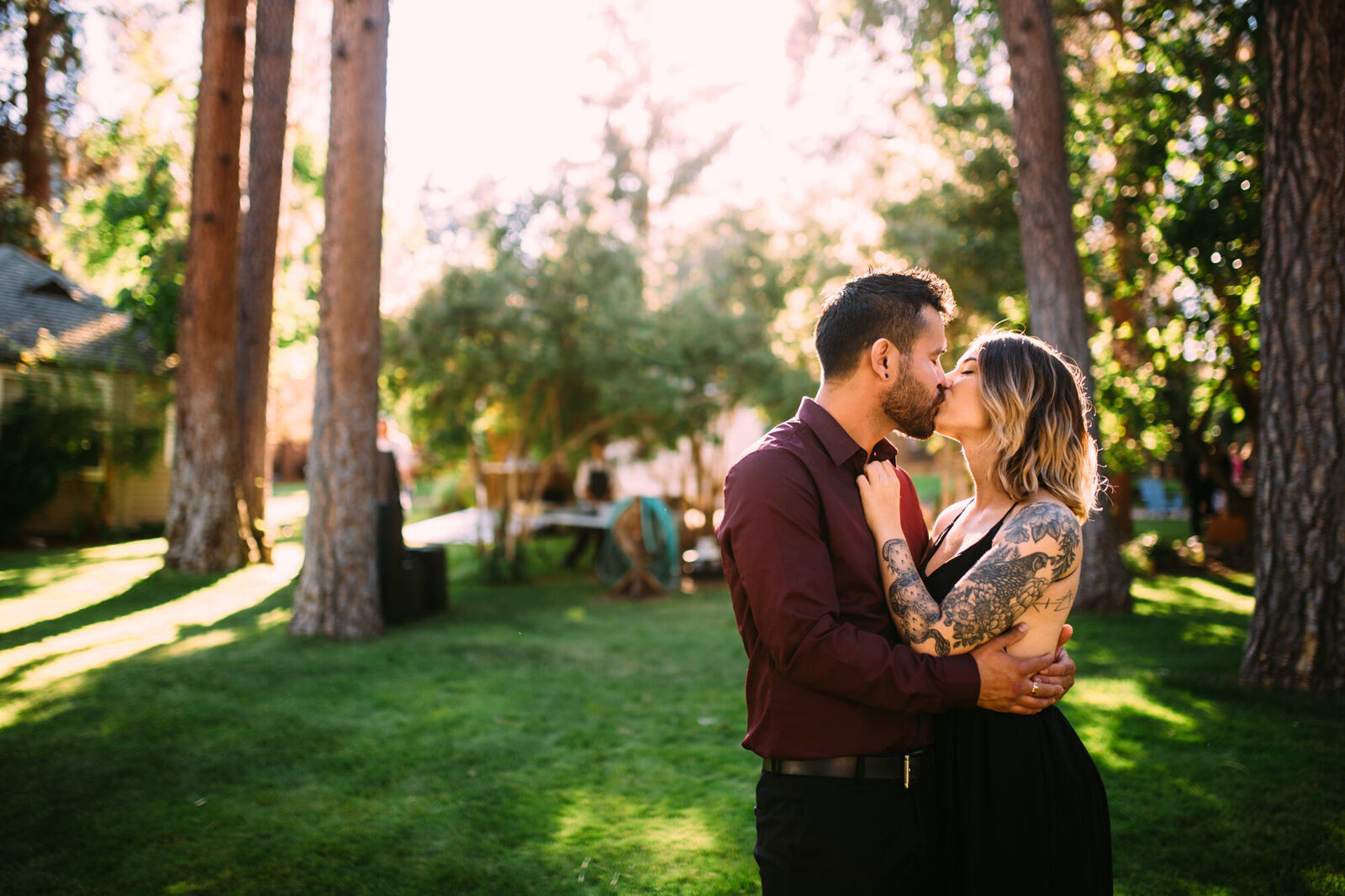 Couple portrait in trees with reception tables behind them