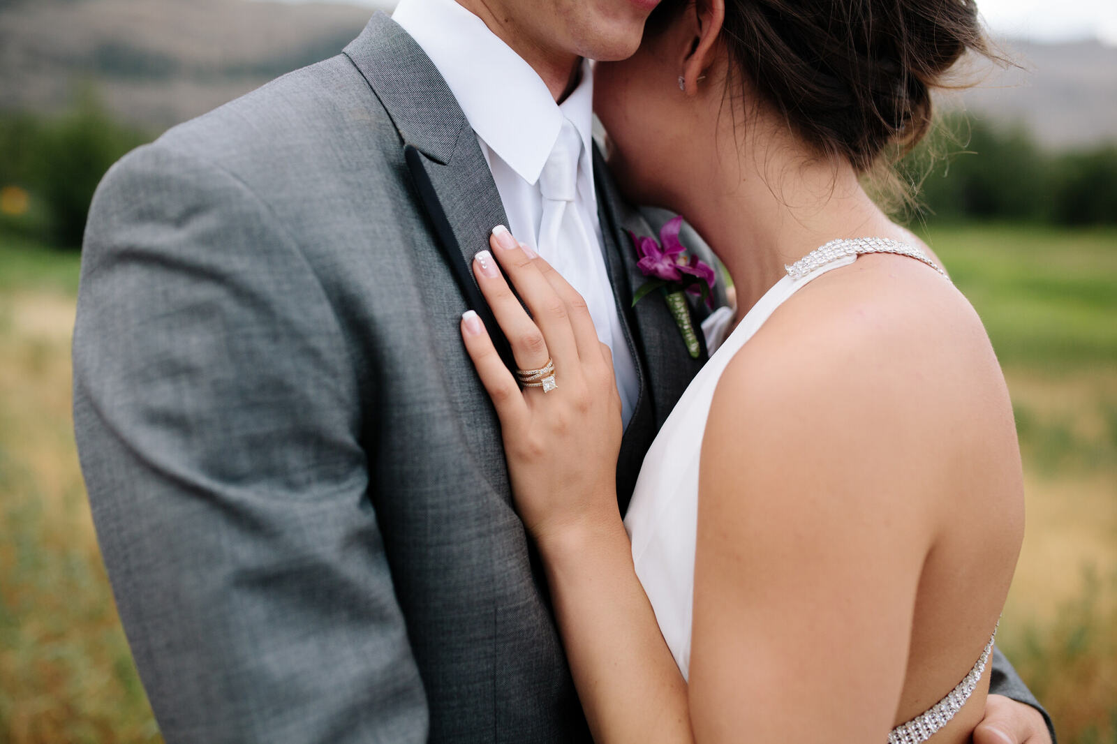 Close portrait of Becky and Nick with hands, rings and soft Osoyoos field light